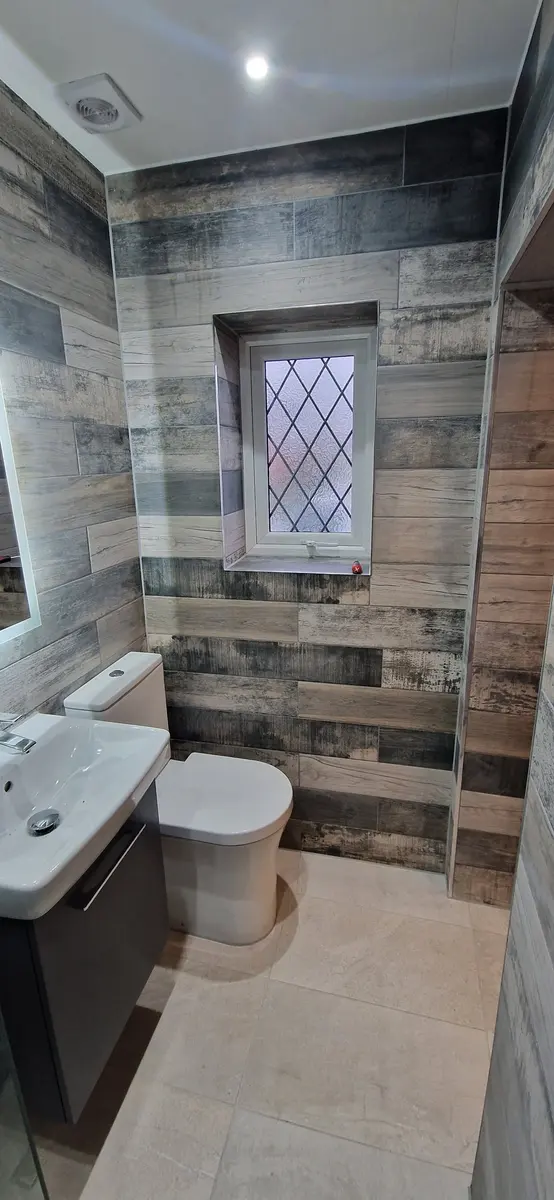 Narrow bathroom with wood-effect wall tiles under a leaded window