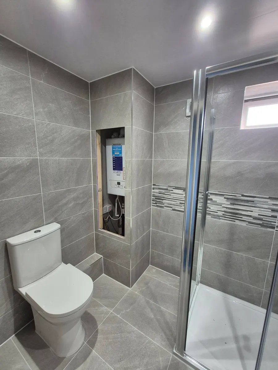 Grey tiled shower room with the boiler boxed into a neat tiled recess
