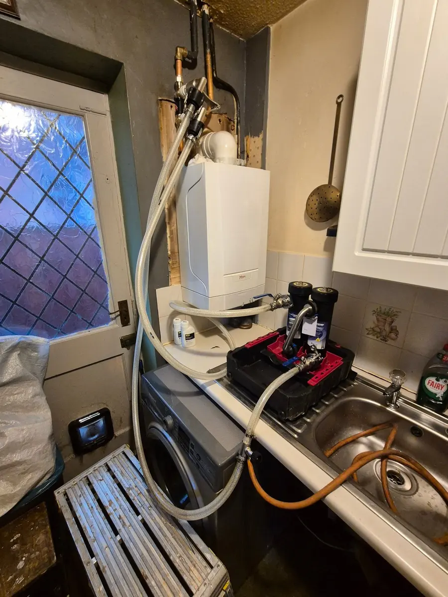 Boiler swap in progress inside a kitchen with flue and pipework exposed